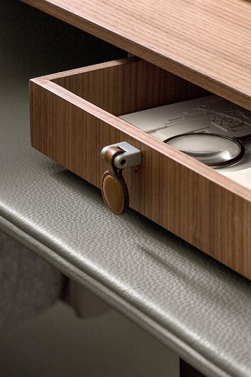 Detail of the curved wooden top covered in leather, the drawer with leather knob and the linear shelf