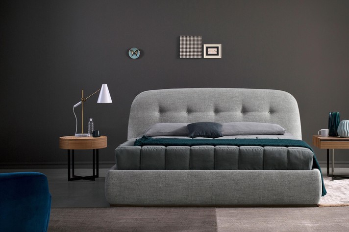 Round bedside table and curved headboard for a relaxing setting