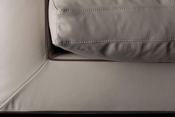 Detail of arm, back and cushion upholstered in leather and detailed with a piping and French seam