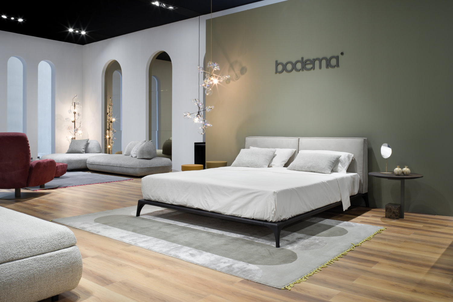 Zona notte allestita con letto e comodini Bodema, stand del Salone del Mobile