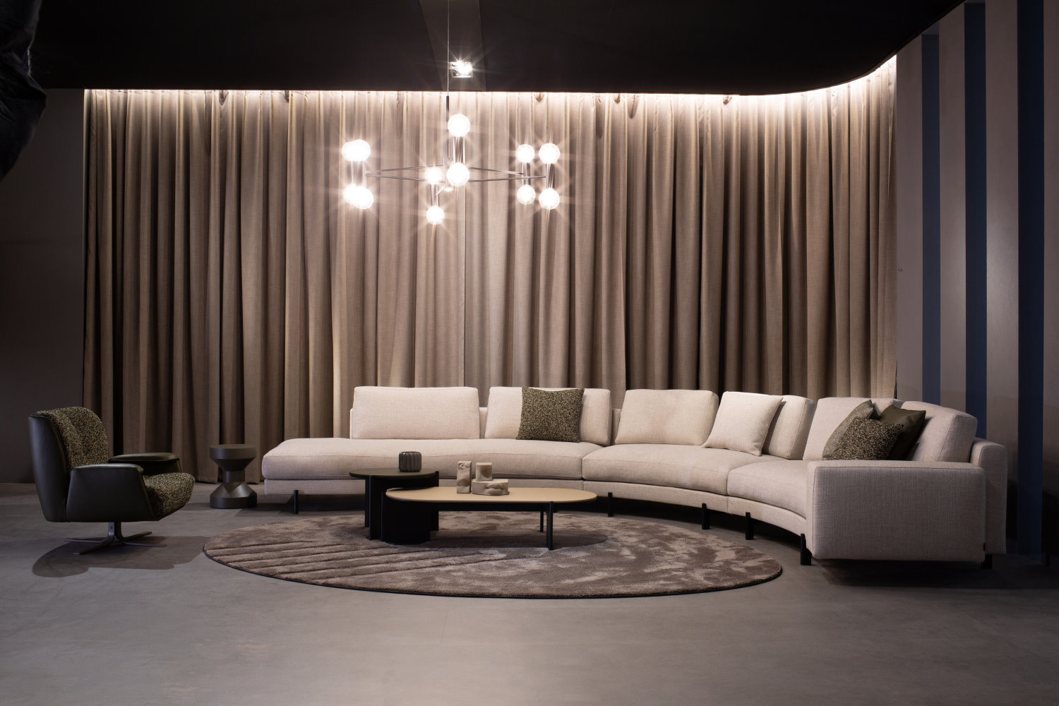 Divano componibile curvo, poltrona e tavolini di Bodema nello stand del Salone del Mobile 2025
